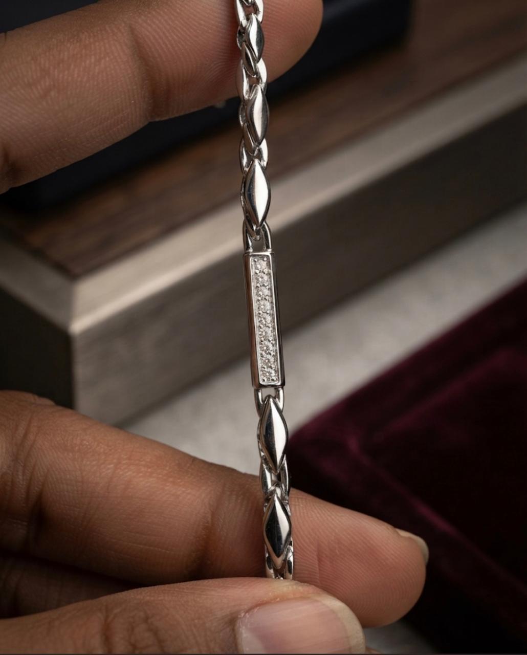 Close-up view of a hand holding a 925 sterling silver bracelet featuring a stone-embellished center bar and marquis links.