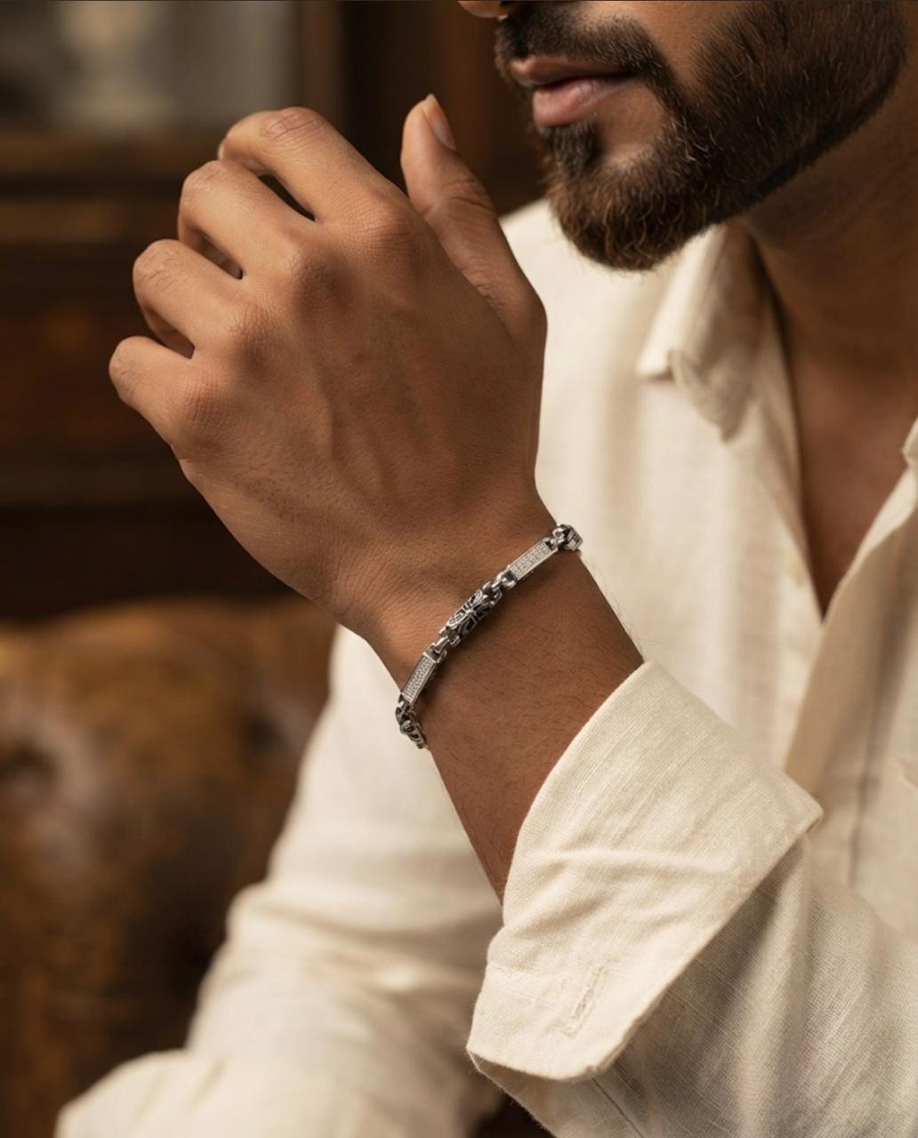 Close-up of a man wearing a 925 sterling silver bracelet with twin engraved bars and cable-style chain links, paired with an off-white shirt.