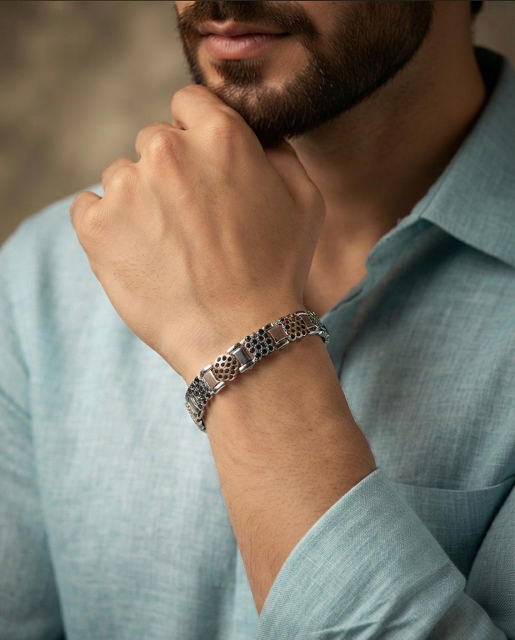 Close-up of a 65% purity silver alloy bracelet with hexa grid textured links worn on a man's wrist with a light blue shirt.