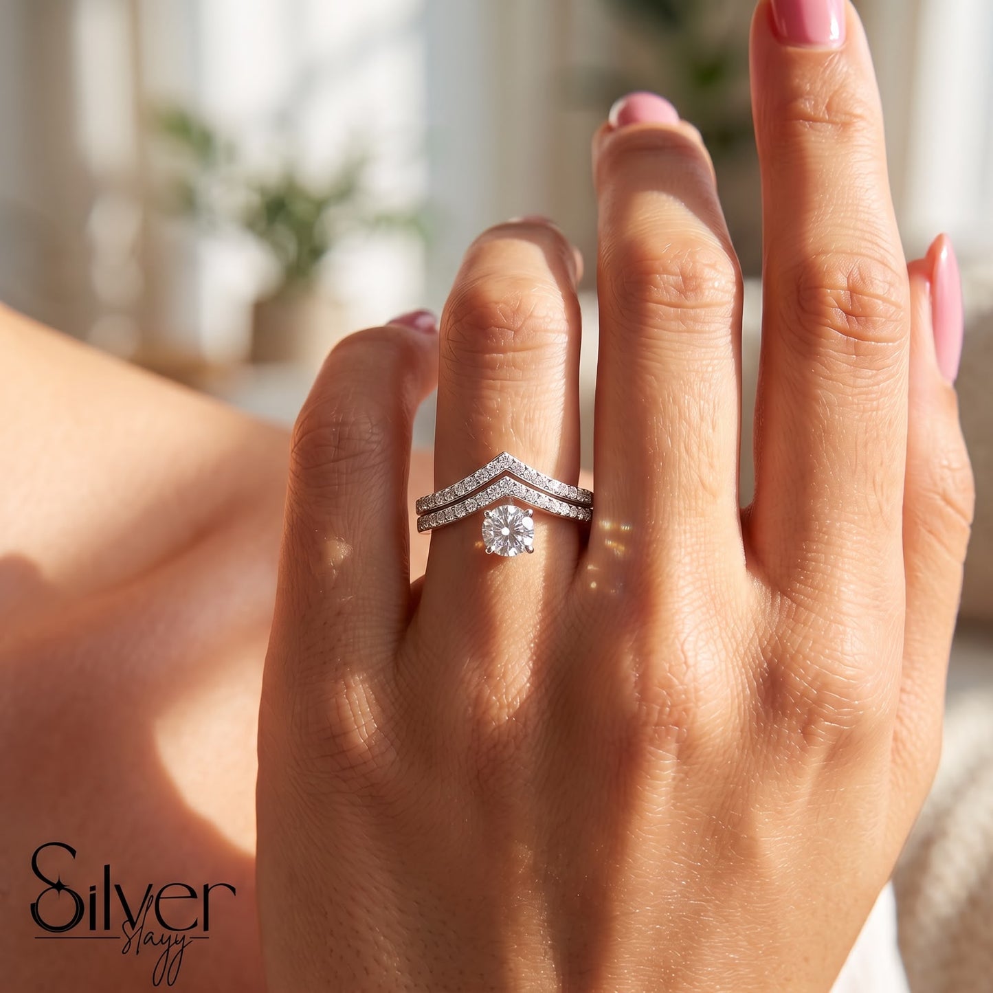 925 sterling silver ring with a round center stone and chevron split band worn on a woman's finger.