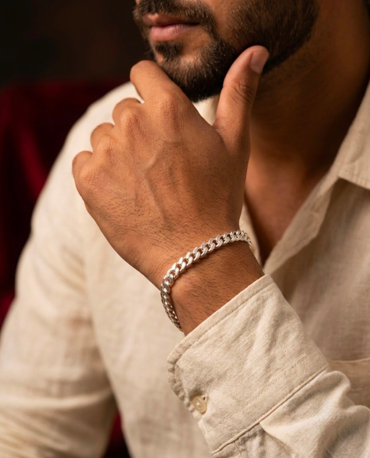 Close-up of a 925 sterling silver Cuban link bracelet worn on a man's wrist with a light linen shirt.