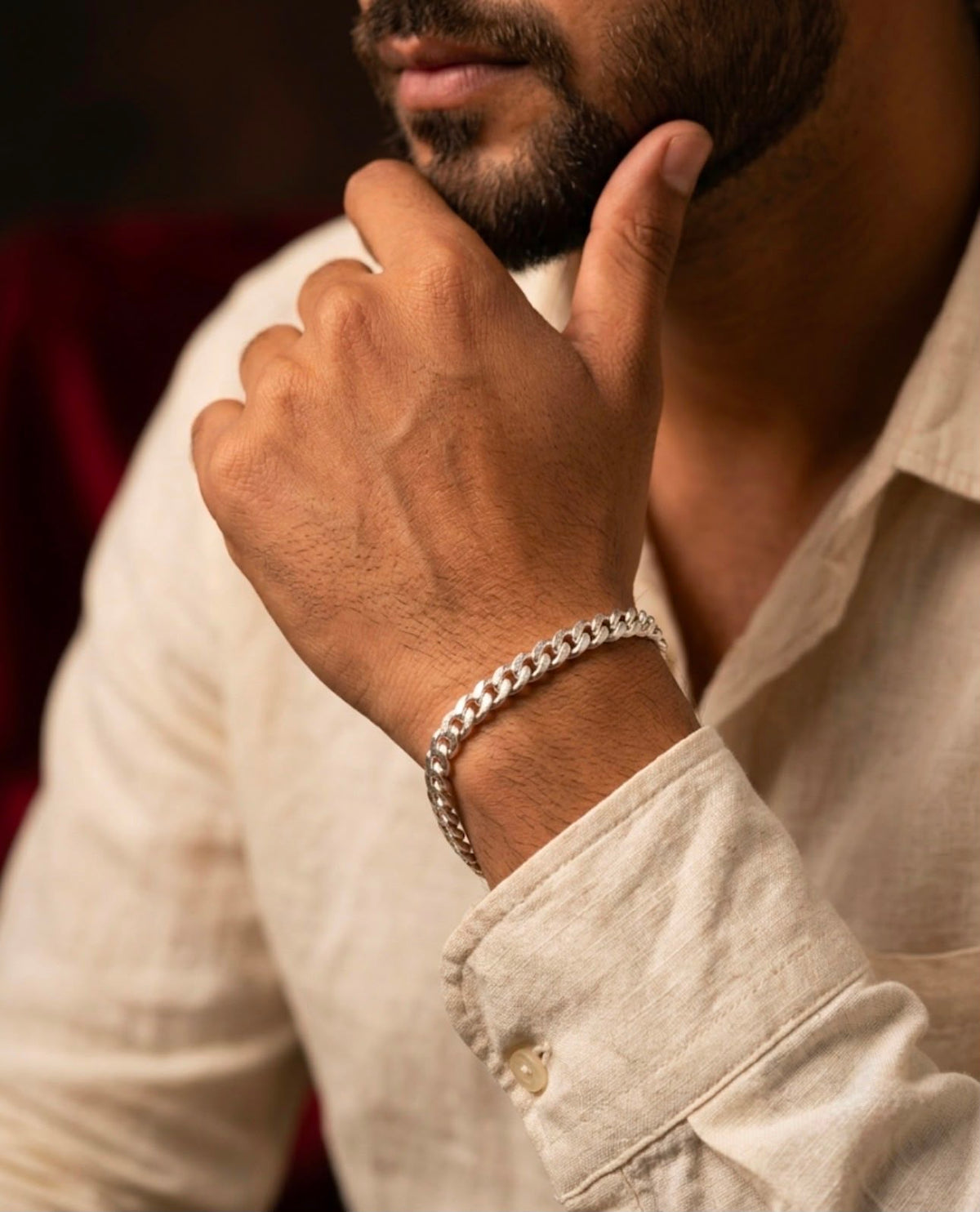 Close-up of a 925 sterling silver Cuban link bracelet worn on a man's wrist with a light linen shirt.