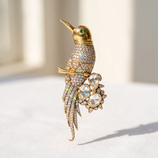 Close-up view of 925 sterling silver perched bird brooch with gold finish and stone embellishments on white surface