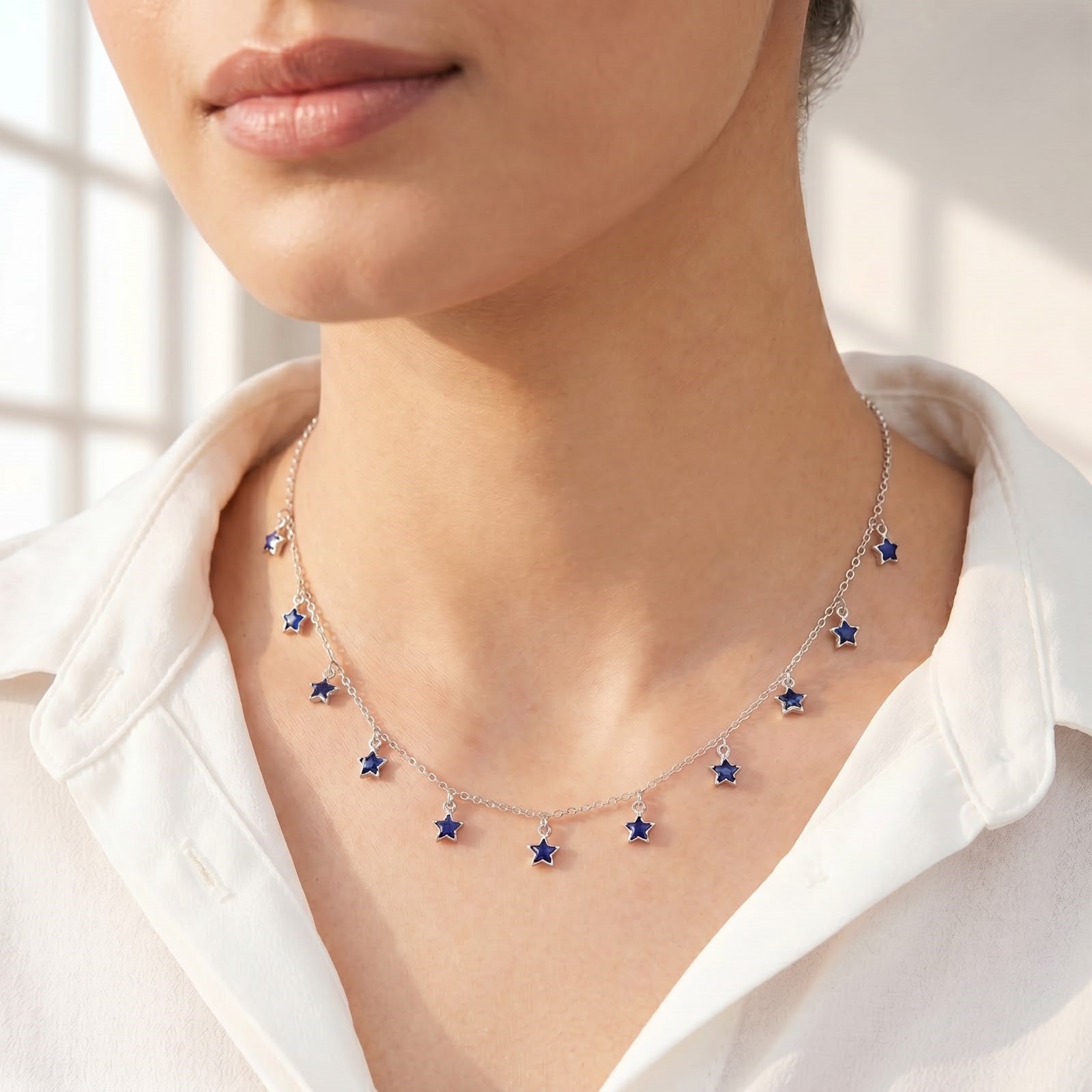 Front view of a 925 sterling silver chain necklace adorned with dangling blue star charms, worn on a woman's neckline.