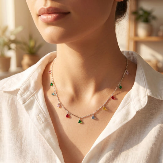 Front view of a 925 silver chain necklace featuring multiple dangling multicolor teardrop charms, styled on a woman's neckline over a white linen shirt.