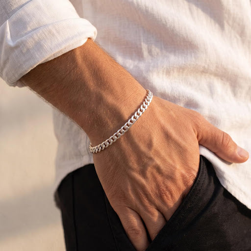 Male wrist wearing a 925 sterling silver curb link chain bracelet paired with a casual white shirt.