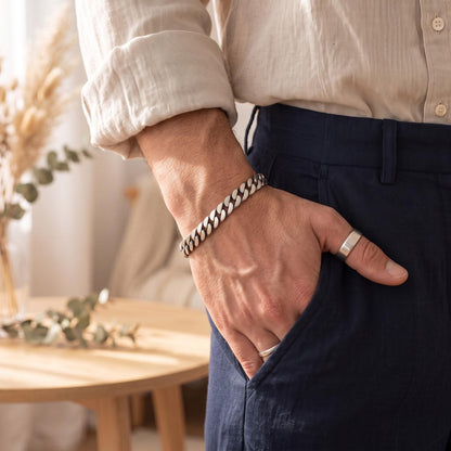 Side angle of a male wrist wearing a thick 925 sterling silver beveled curb link chain bracelet
