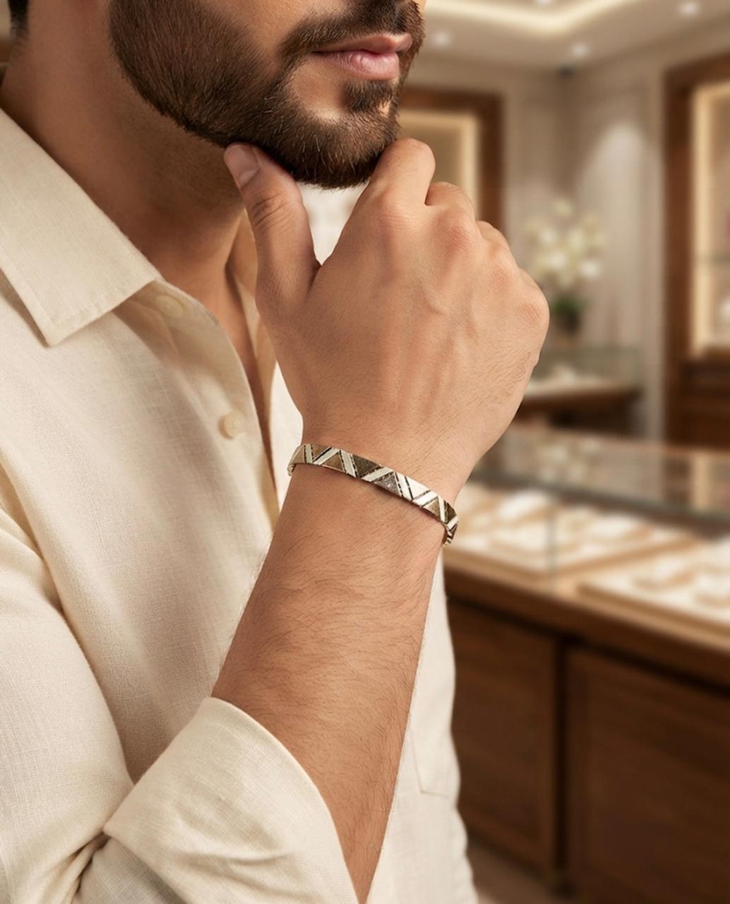 Close-up of a man wearing a 925 sterling silver bracelet with angular mosaic links, paired with an off-white shirt in a jewellery showroom.