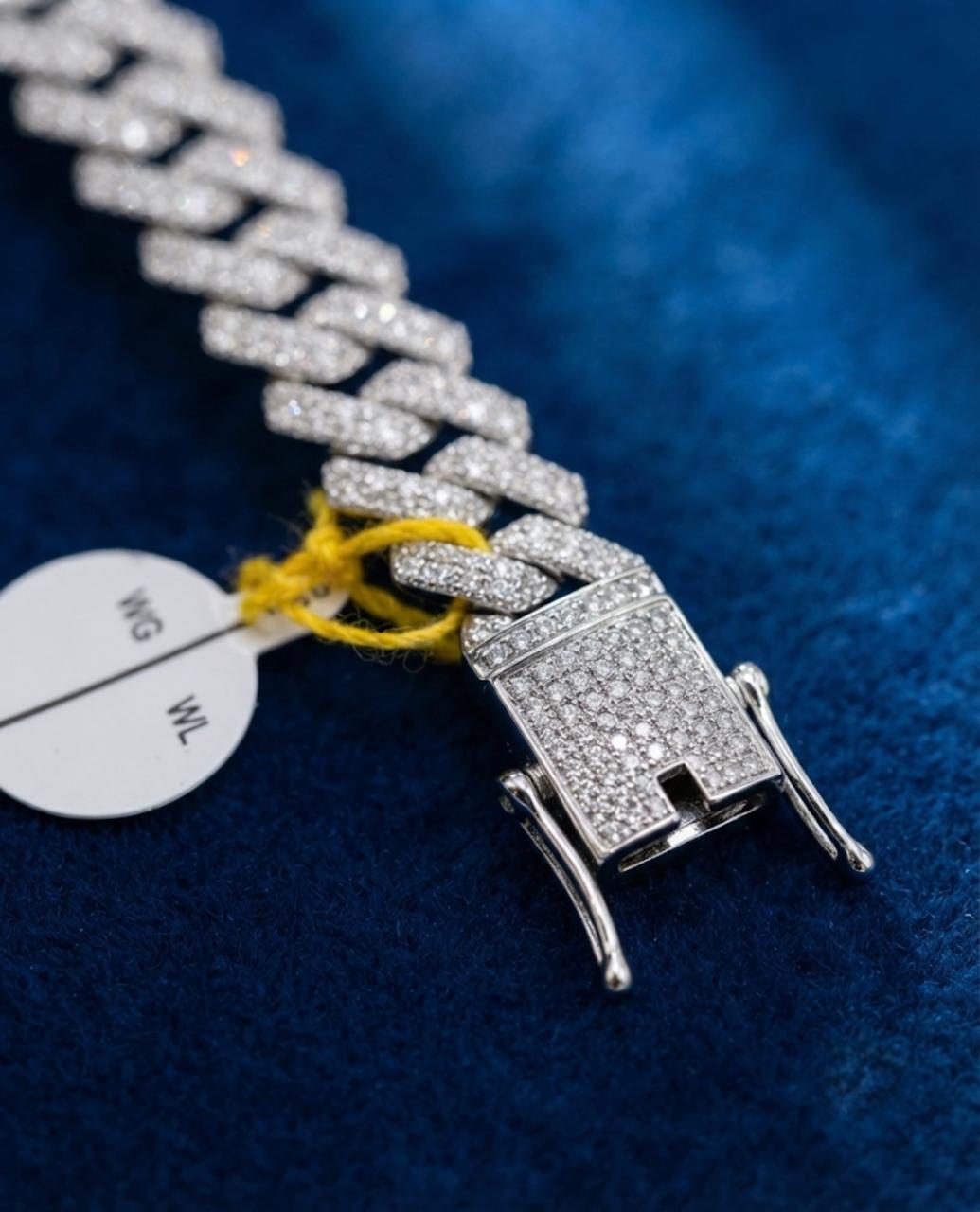 Close-up view on blue velvet of a 925 sterling silver Cuban link bracelet with full pave stones and dual safety box clasp.