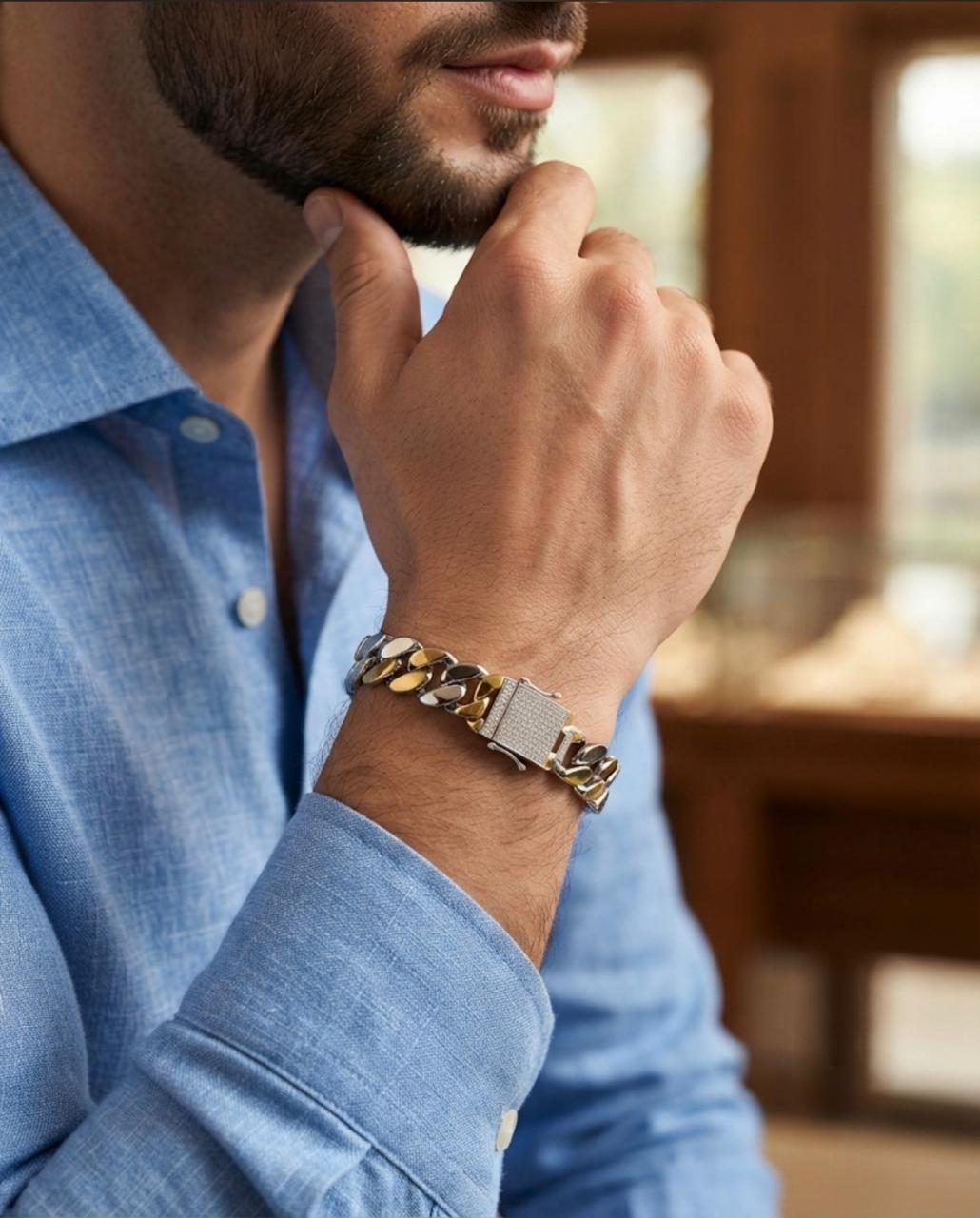 Close-up of a 925 sterling silver dual-tone Cuban link bracelet with a textured clasp worn on a man's wrist with a blue shirt.