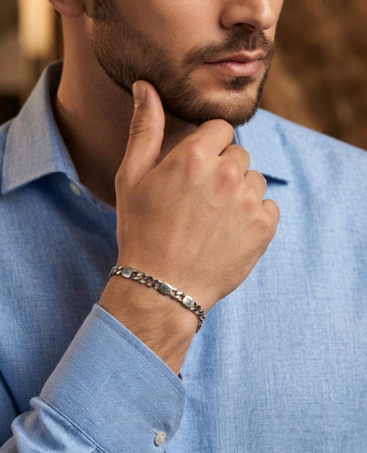 Close-up of a man wearing a 925 sterling silver bracelet with Greek key accent links and polished chain connectors, paired with a light blue shirt.