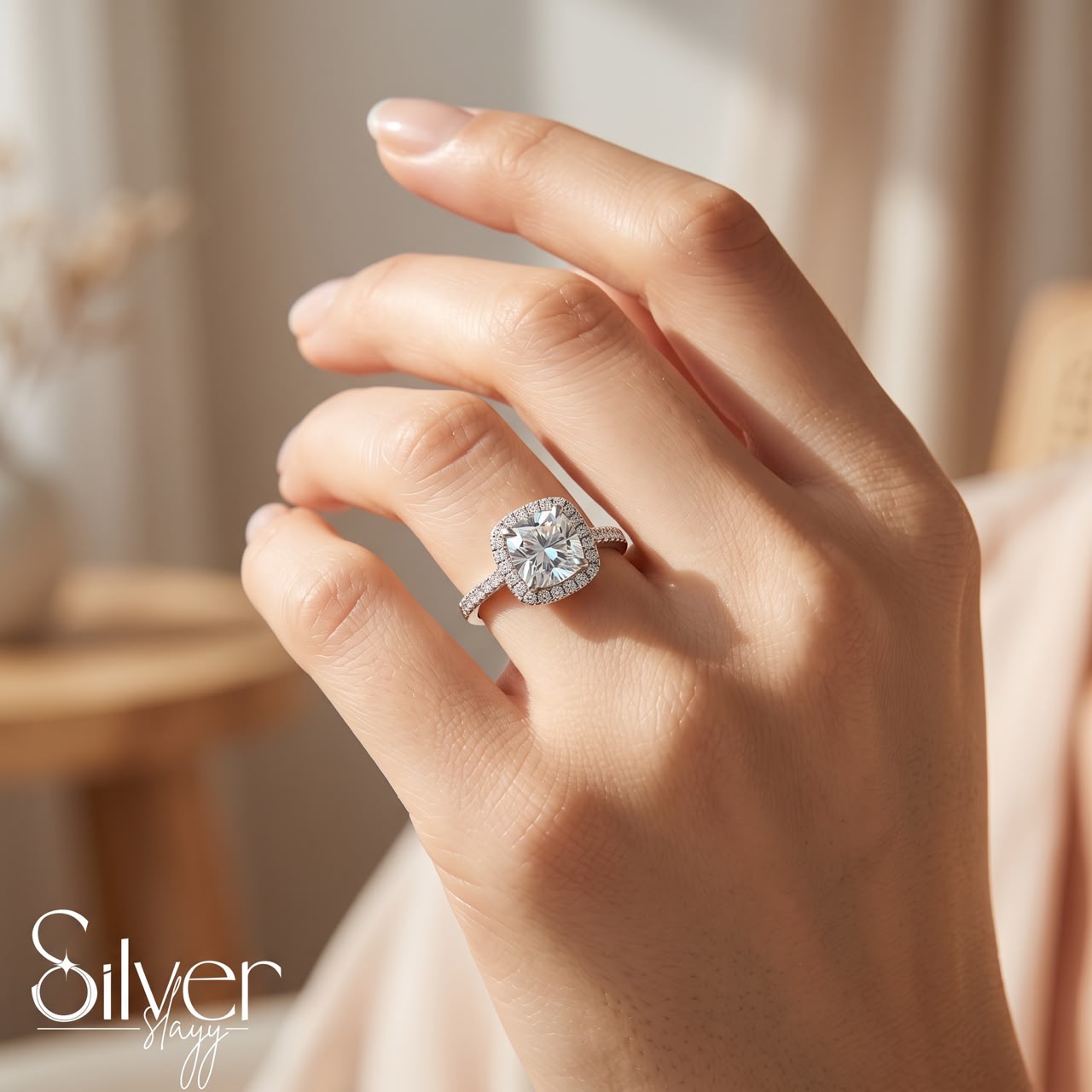 Close-up of a 925 sterling silver ring with a cushion halo and round centre stone worn on a woman's finger in natural light.