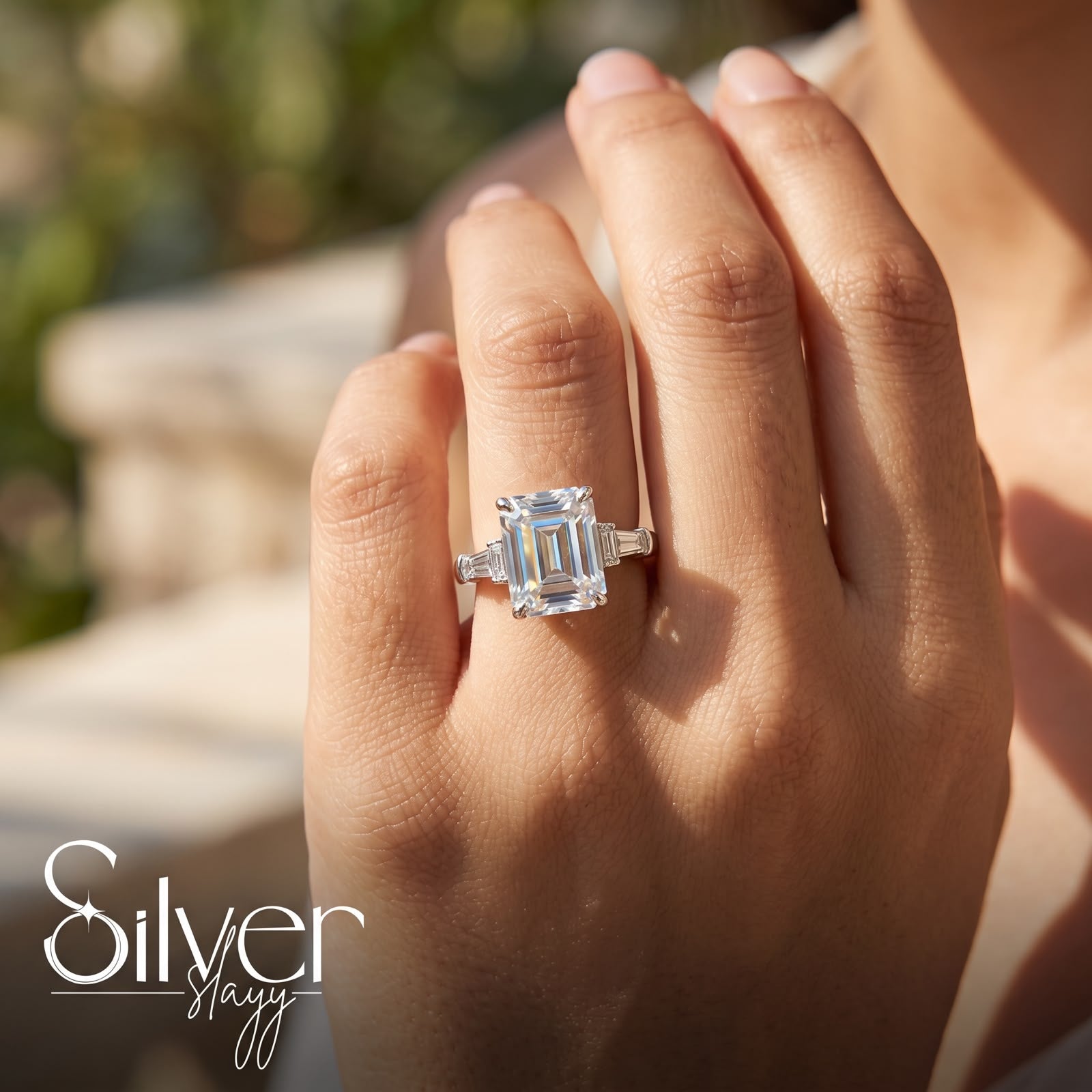 925 sterling silver ring with an emerald-cut center stone and side stones worn on a woman's finger.