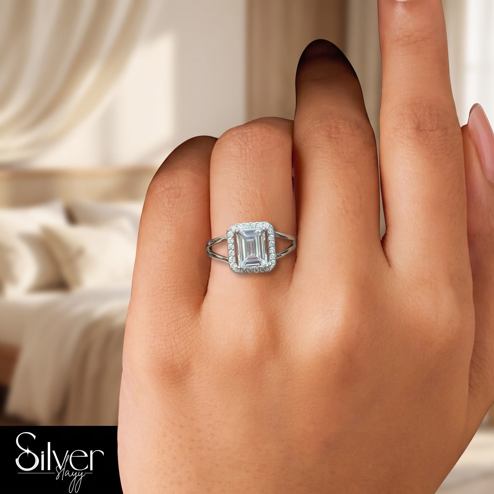 925 sterling silver ring with an emerald-cut center stone and halo frame worn on a woman's finger.