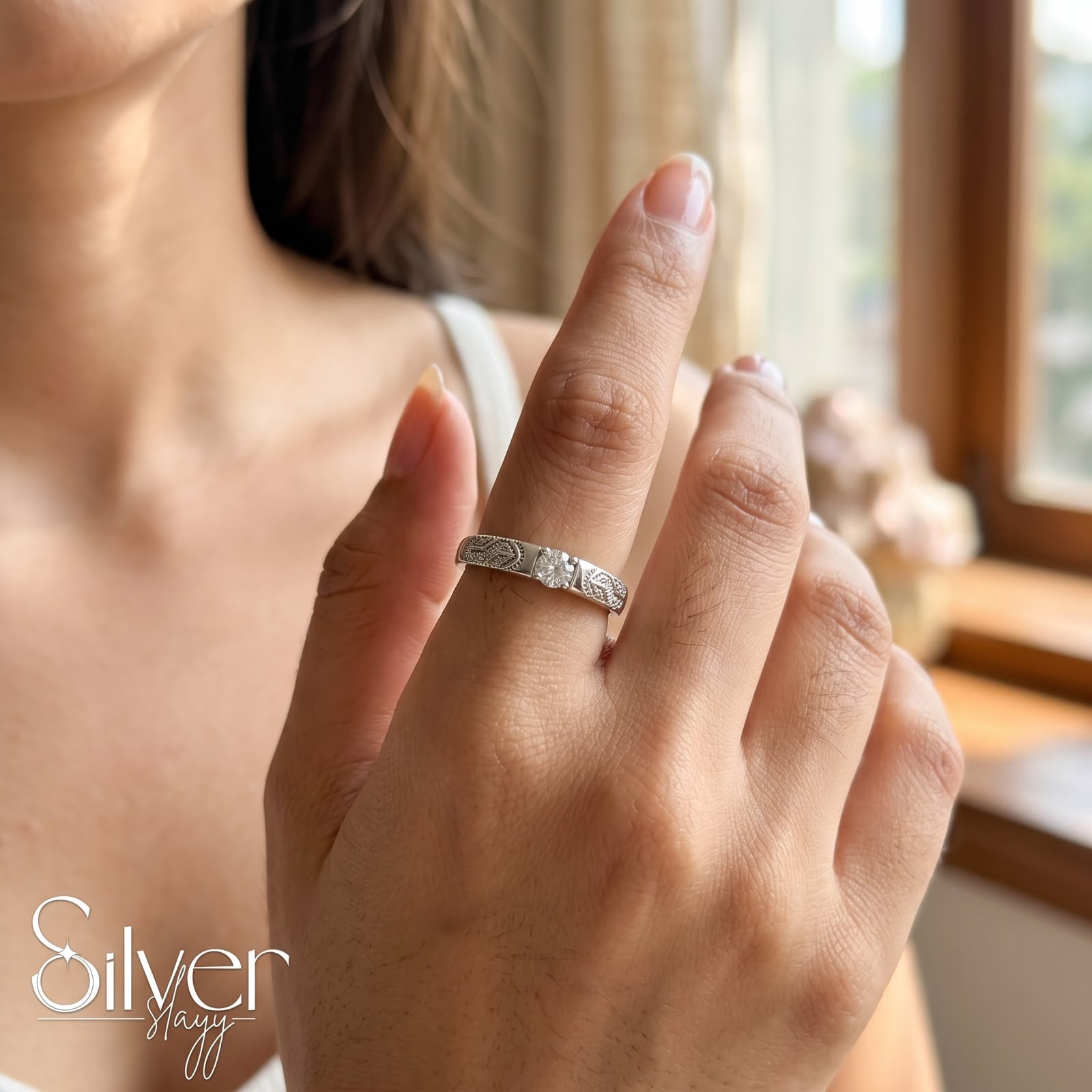 925 sterling silver ring with a round center stone and engraved band worn on a woman's finger.