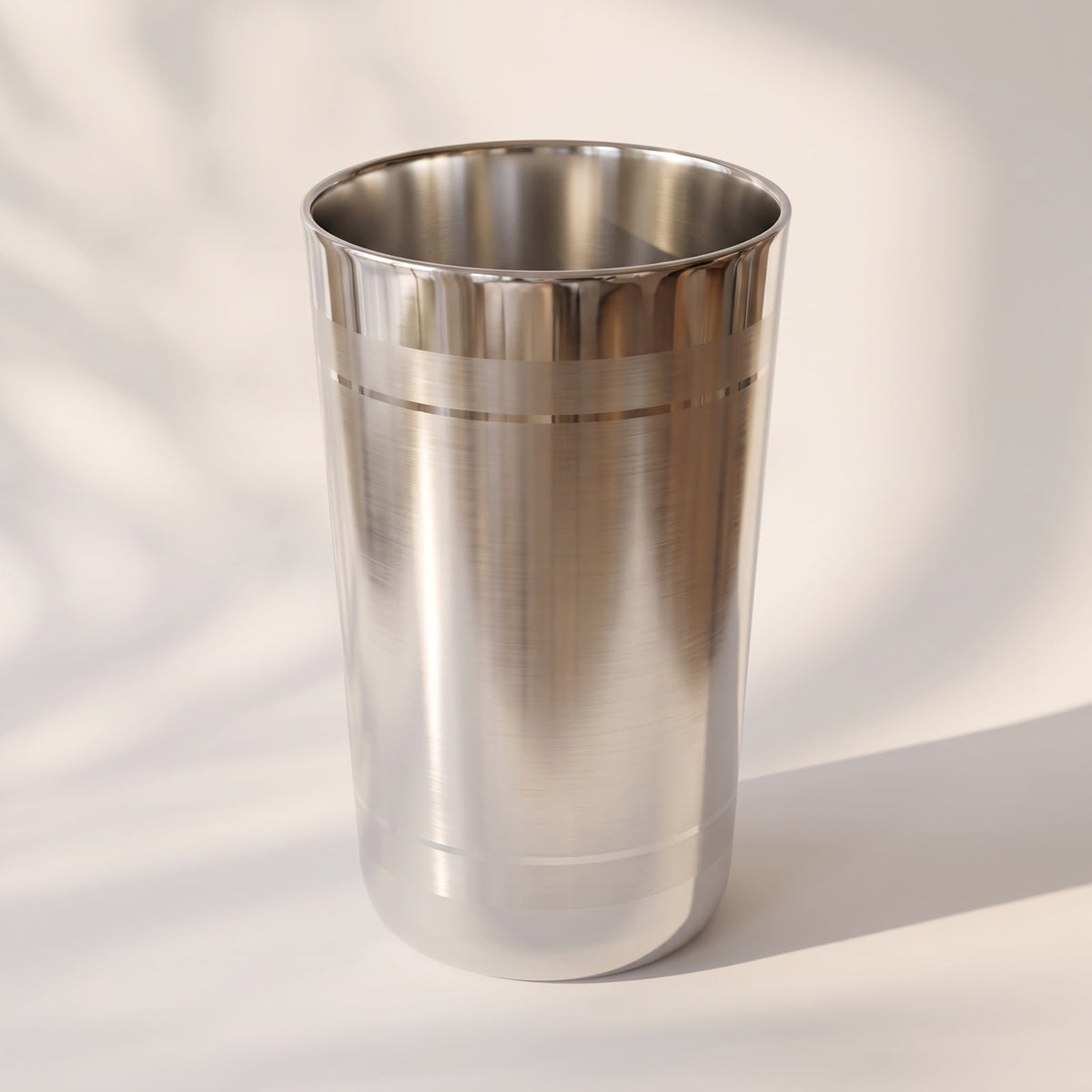 Angled view of a 925 sterling silver tumbler with brushed body and polished ring grooves on a light surface