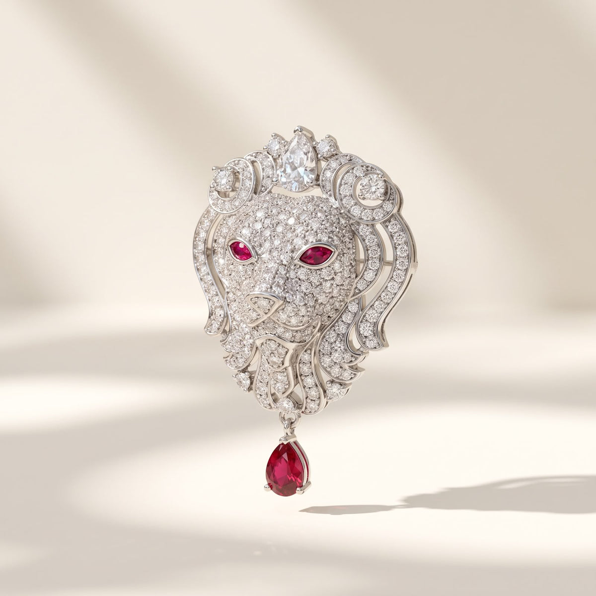 Front view of 925 sterling silver lion head brooch with micro pave stones, red stone eyes, and dangling teardrop on white surface.