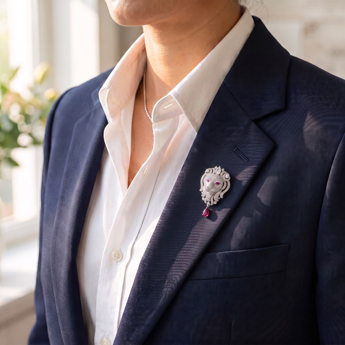 925 sterling silver lion face lapel pin with red drop stone worn on dark navy suit blazer for men.