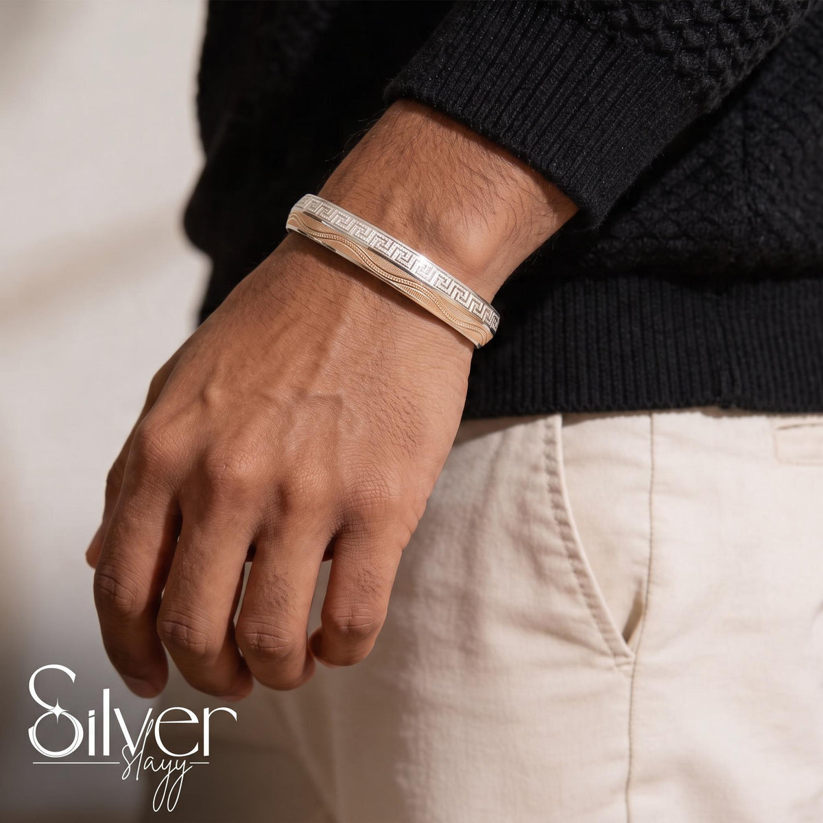 Man wearing a 925 sterling silver bracelet for him with a Greek key border pattern and layered linear detailing on the wrist.