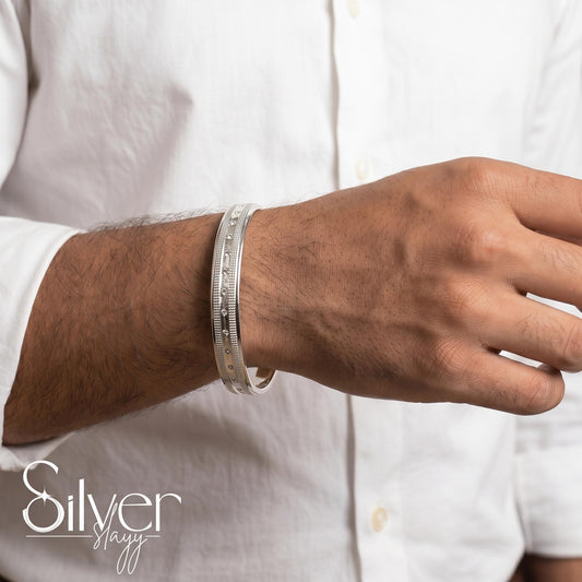 Man wearing a 65% purity silver bracelet with dotted accents and textured borders on his wrist, styled with a white shirt.