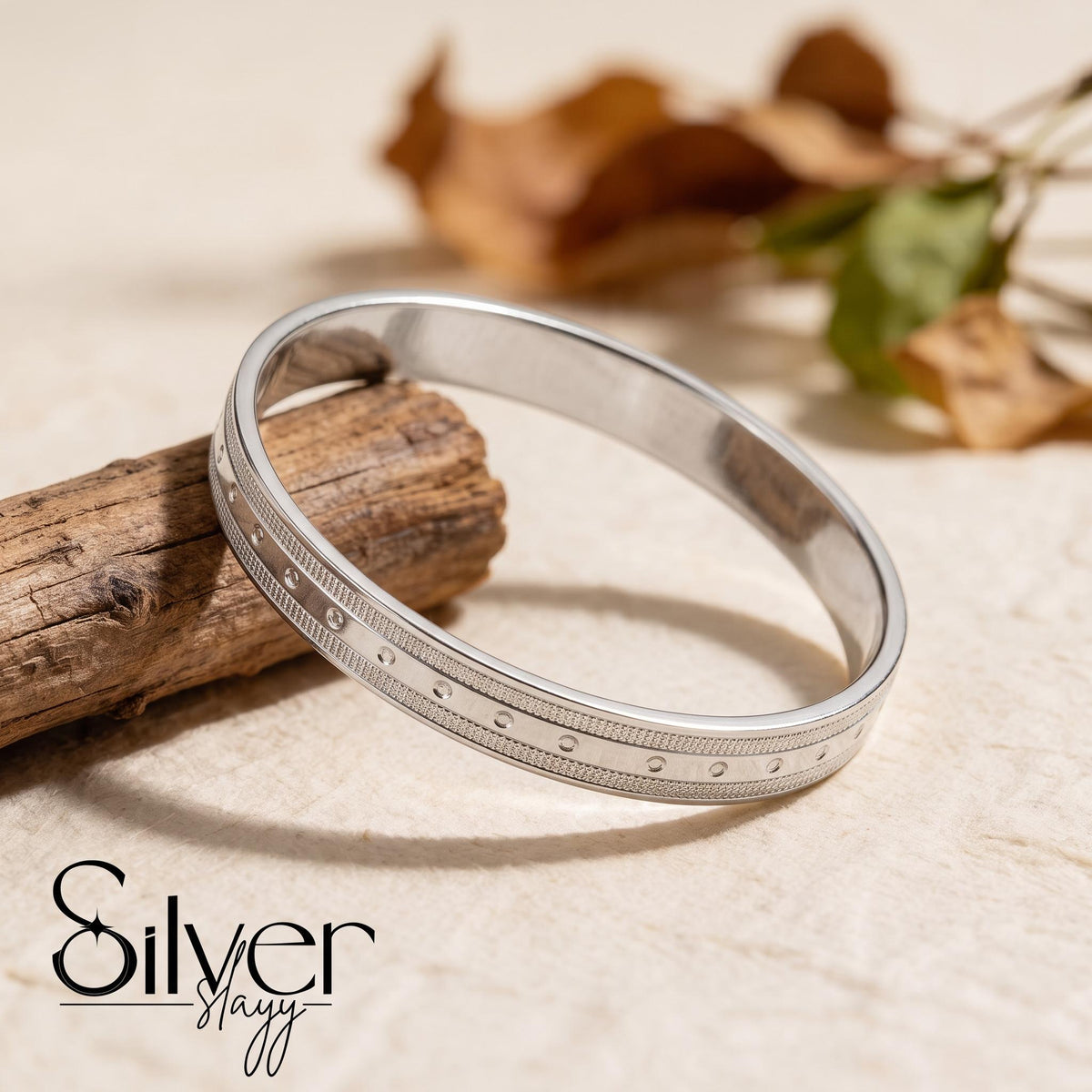 65% purity silver bracelet for him displayed on a wooden surface, showing its dotted accent row, textured borders, and polished edges.
