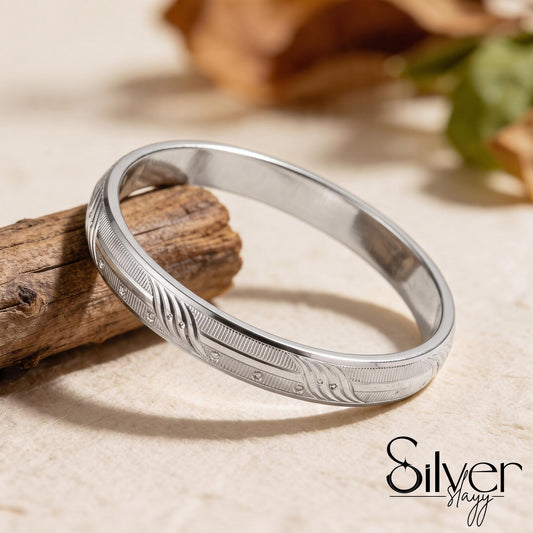 925 purity silver bracelet for him displayed on a wooden surface, showing flowing curved engravings, textured lines, circular accents, and polished edges.