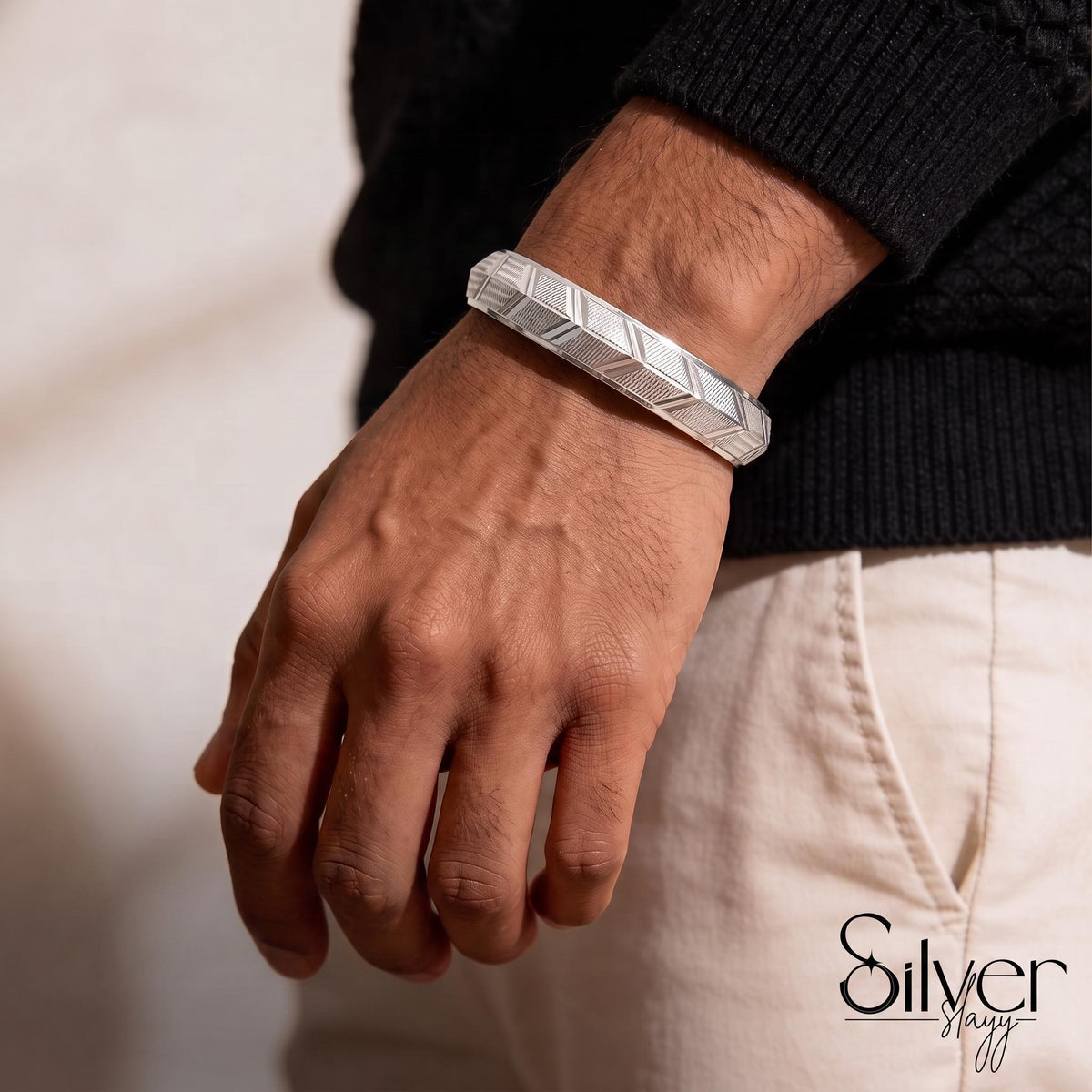 Man wearing a 65% purity silver bracelet featuring a geometric engraved pattern with alternating textured panels on his wrist.