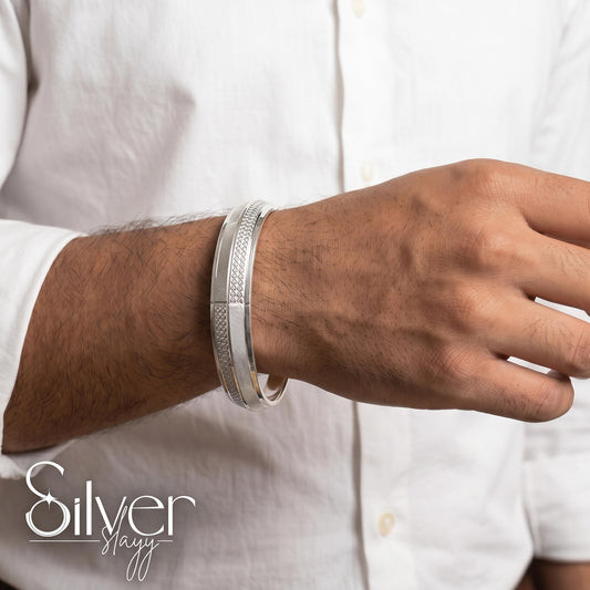 Man wearing a 925 purity silver bracelet with circular textured accents and fine linear detailing on his wrist, styled with a white shirt.