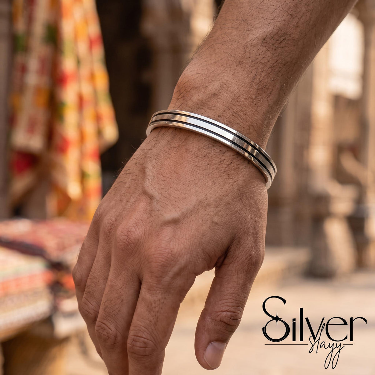 Man wearing a 925 silver bracelet with a smooth central band and textured parallel edges on his wrist.