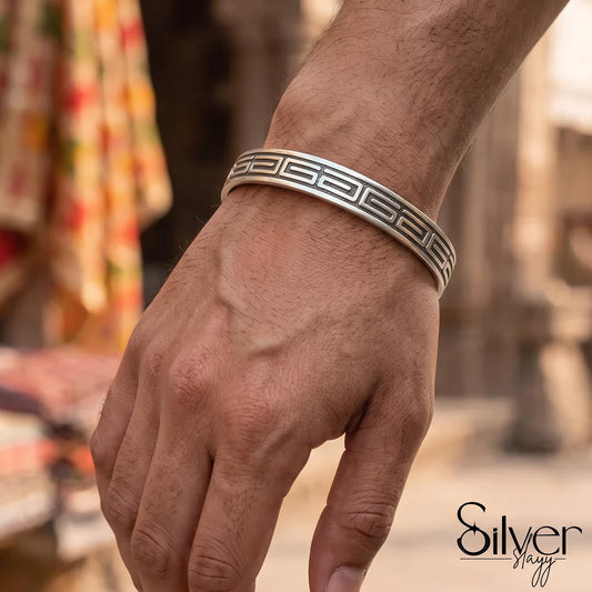 Man wearing a 925 silver bracelet with repeating Greek key geometric engraving and openable cuff design