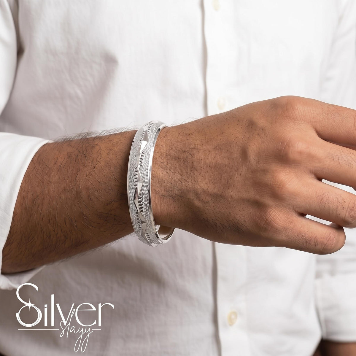 Man wearing a 925 purity silver bracelet with angular leaf-style engraved detailing on his wrist.
