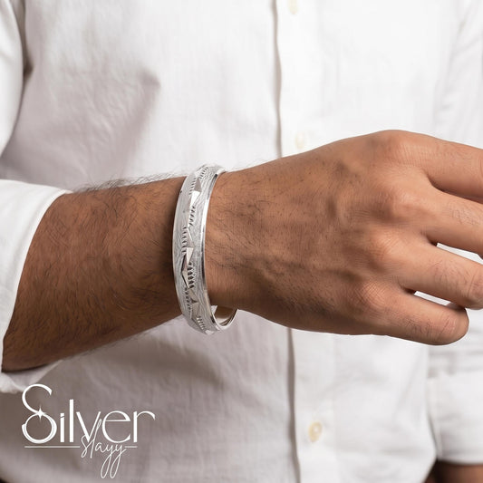 Man wearing a 925 purity silver bracelet with angular leaf-style engraved detailing on his wrist.