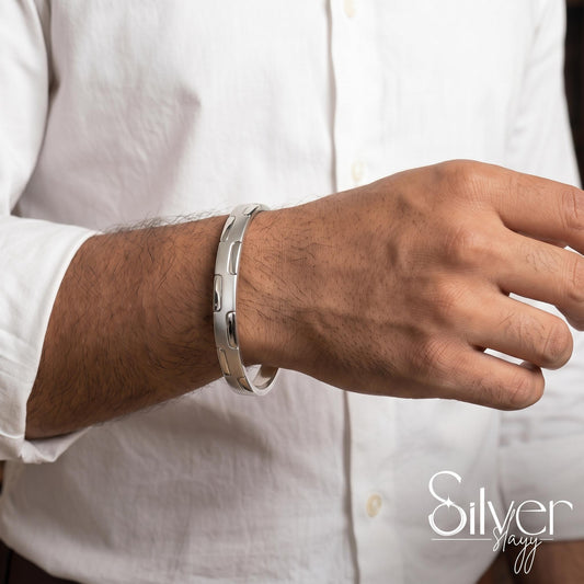 Man wearing a 925 silver bracelet with raised oval segment detailing on his wrist.
