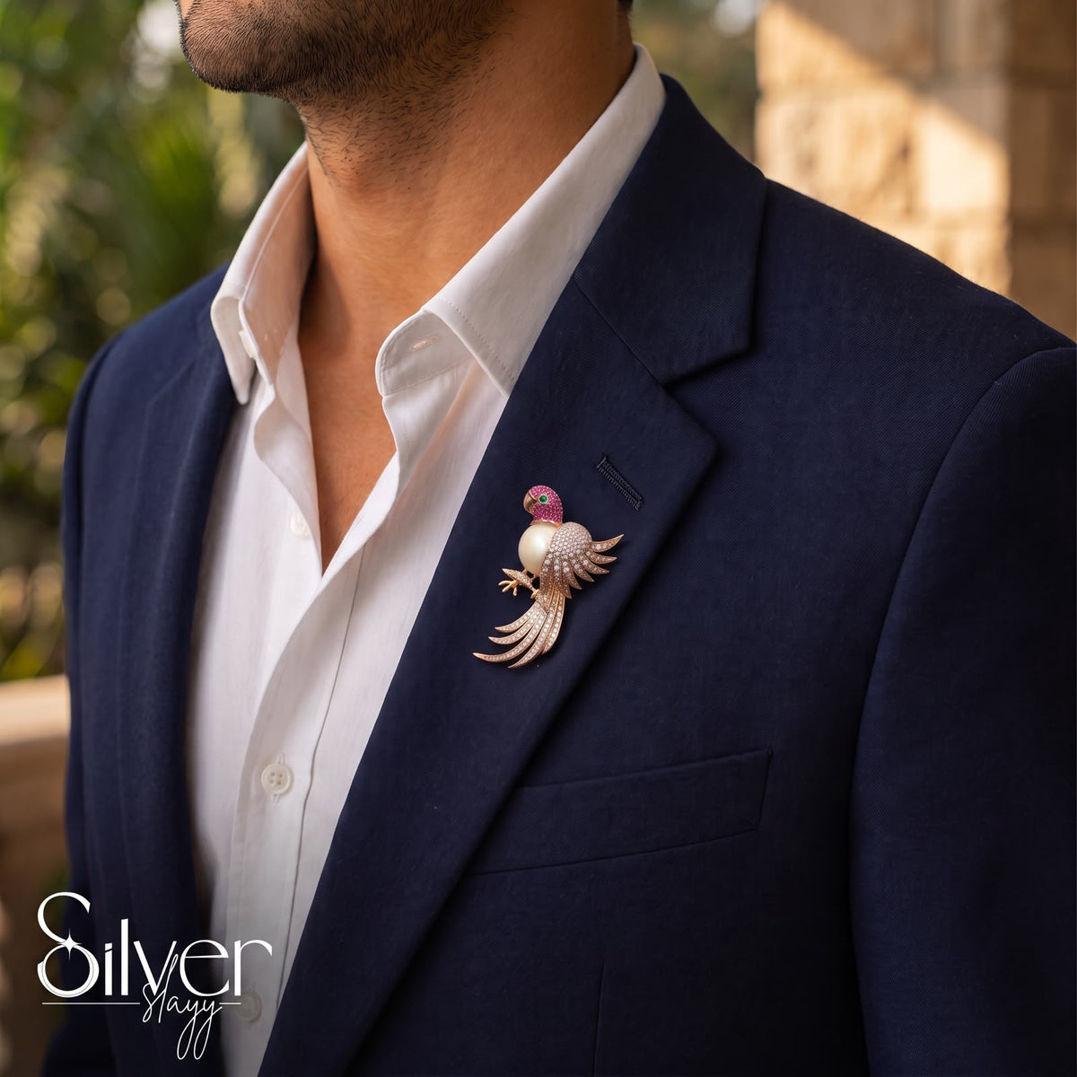 925 sterling silver parrot brooch with pearl body and rose gold finish styled on the lapel of a navy suit jacket.